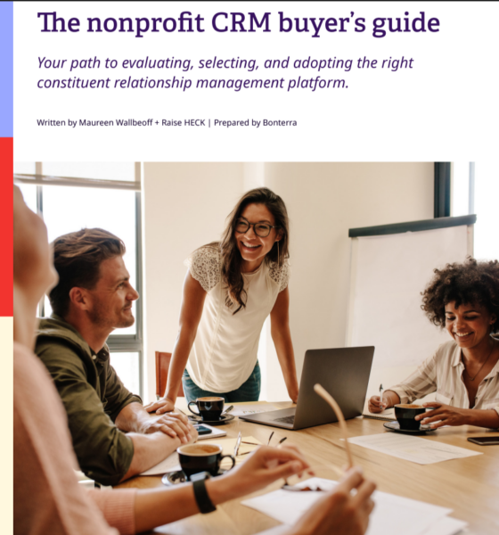 Thumbnail copy of the cover of the Nonprofit CRM Buyers Guide with people on the cover at a work desk with computers laughing and having a great time buying nonprofit software